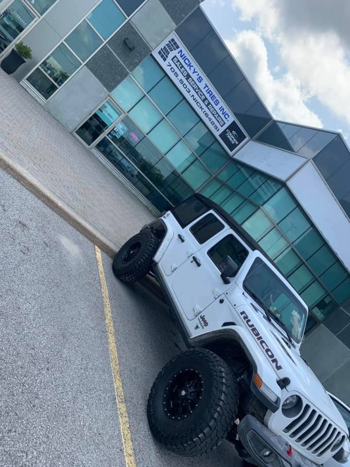 White Jeep Rubicon with aggressive off-road tires outside Nicky's Tires
