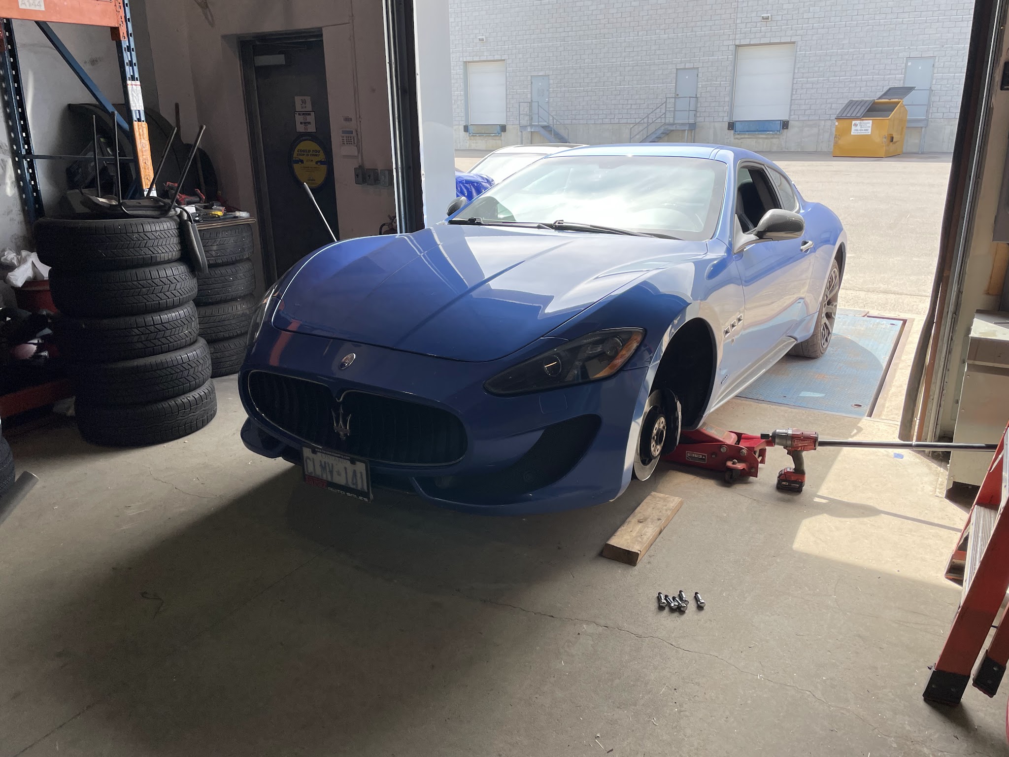 Blue Maserati getting tire service in the shop